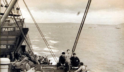 Troops on Board a Landing Craft at D Minus 1 Sit Around on Deck, Mostly Silent, and Look at the Last Glimpses of the Mainland Behind Them