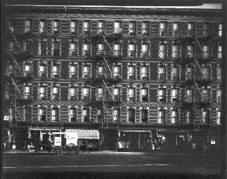 Untitled (front view of building with storefronts and horse drawn cart)