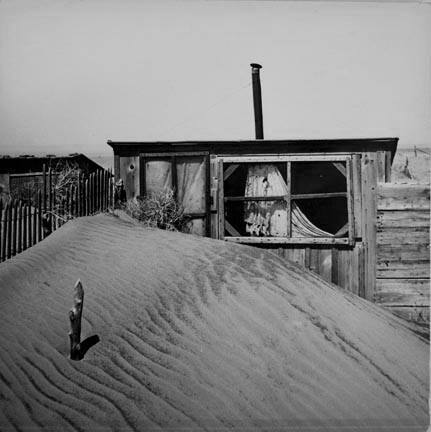 Sand piled up in front of outhouse on farm. Cimarron County, Oklahoma