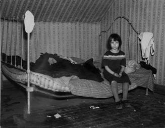 One of Edgar Allen's children sitting on the bed in the house on his farm. There are no sheets, pillowcases, or pillows (other than makeshift) in use. Bedding usually consists of castoff rags and a few old blankets. Near Milford, Iowa. They are helped by the Resettlement Administration