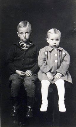 Untitled (two children in coats, seated on table)