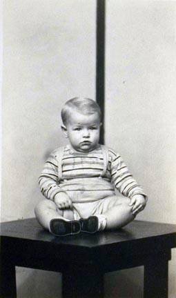 Untitled (baby seated on table wearing striped shirt)