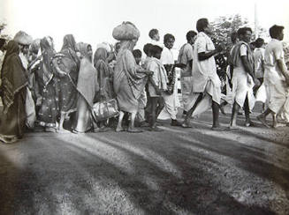 LL1156 (line of people walking in the street, men in front, women in back)