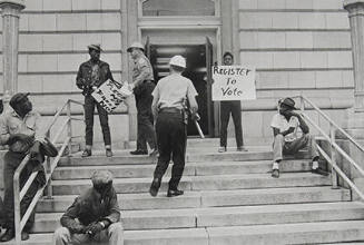 Sheriff Jim Clark arrests two demonstrators who displayed placards on the steps in front of the federal building in Selma