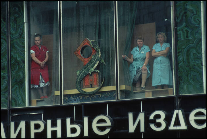 Three department store workers watch a mass funeral from the store window following the failed coup attempt, Moscow, Russia