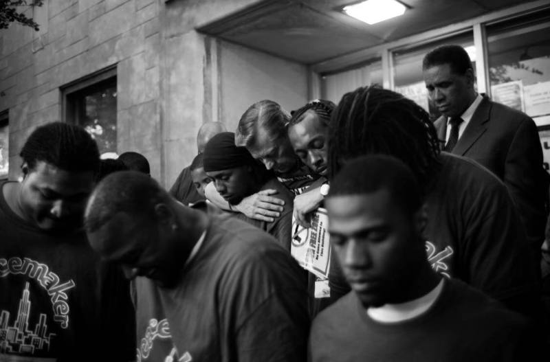 Rev. Michael Pfleger of St. Sabina Church embraces young men who are working to break the cycle of violence during a prayer service, Auburn Gresham, Chicago,