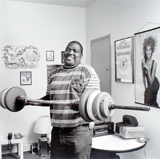 Young man lifting weights in his room at the Harold Washington SRO, from the Edge of Shelter Project